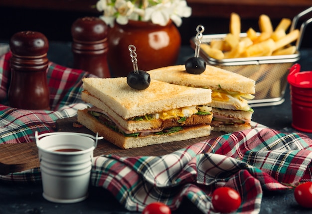 Club sandwich con huevos, lechuga, salami, pepino, tomate, servido con papas fritas