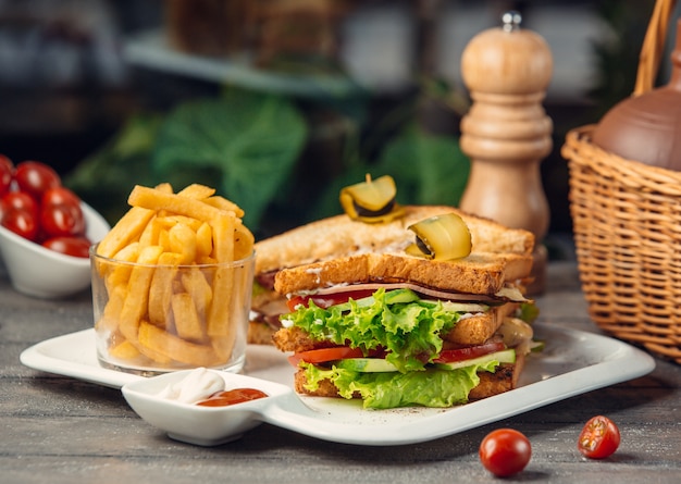 Club sandwich con lechuga, tomate, pepino, pechuga de pavo, papas fritas