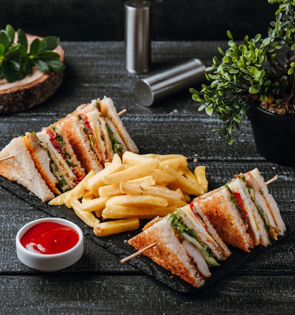 Foto gratuita club sandwich con papas fritas en la mesa