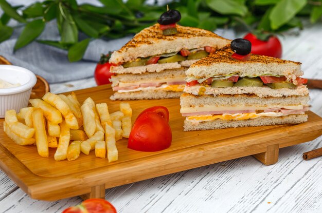 Club sandwich con papas fritas en tablero de madera