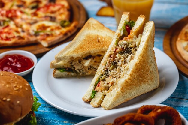Club sandwich pechuga de pollo lechuga queso tostadas pan tomate pepino papas fritas vista lateral