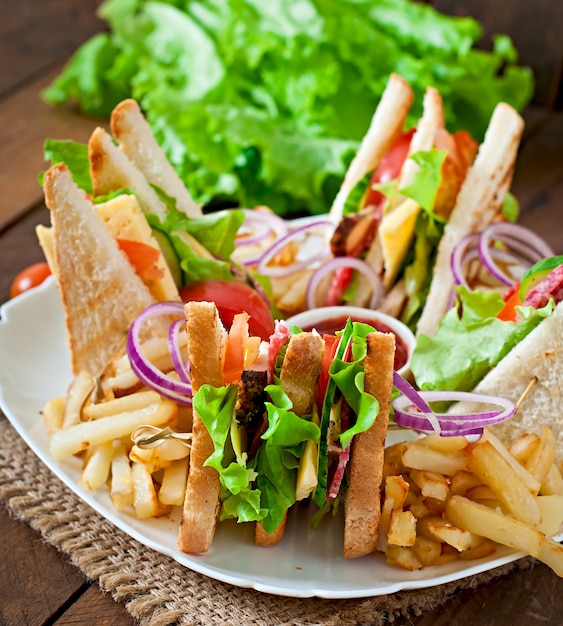 Club sandwich con queso, pepino, tomate, carne ahumada y salami. Servido con papas fritas.