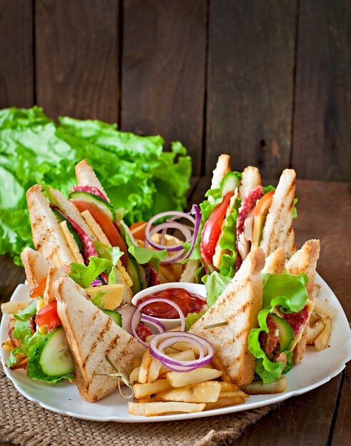 Club sandwich con queso, pepino, tomate, carne ahumada y salami. Servido con papas fritas.