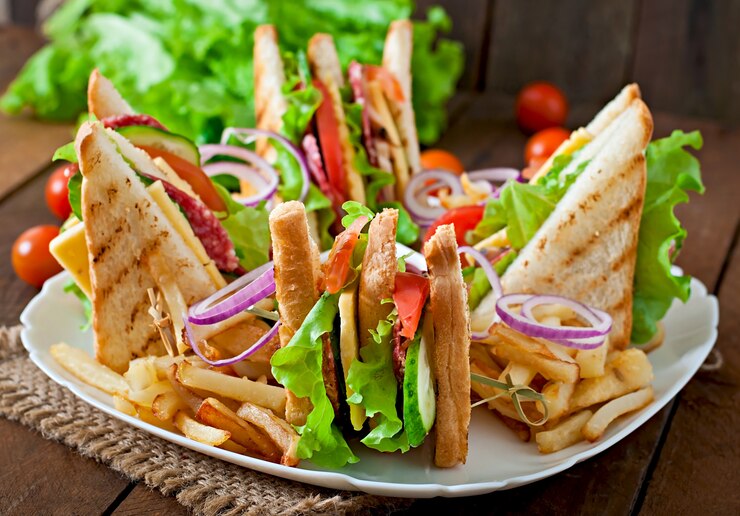 Foto gratuito club sandwich con queso, pepino, tomate, carne ahumada y salami. servido con papas fritas.