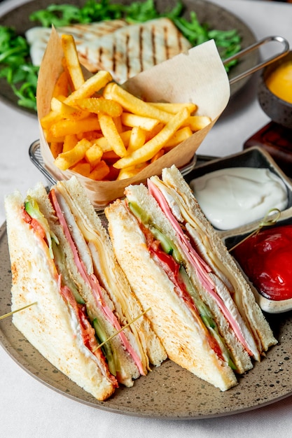 Club sandwich servido con papas fritas ketchup y mayonesa