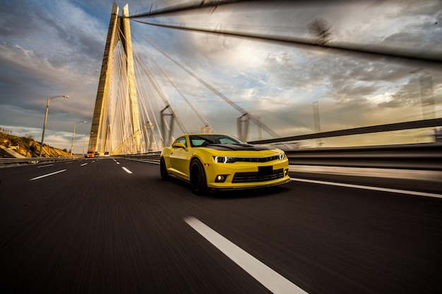 Foto gratuita coche deportivo amarillo con autotuning negro en el puente.