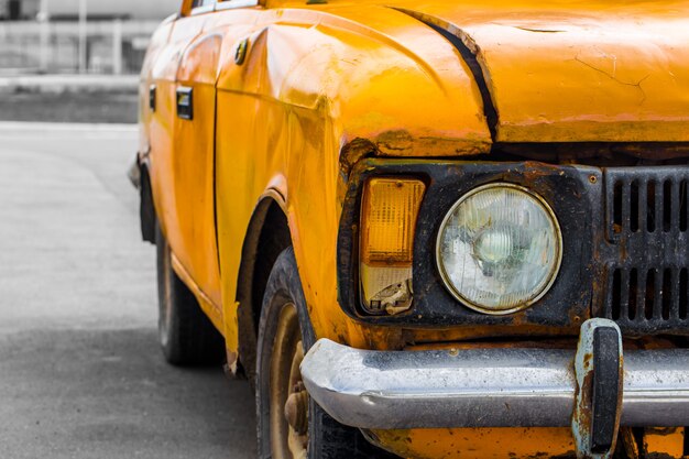 Coche de época amarillo. De cerca. Roto.