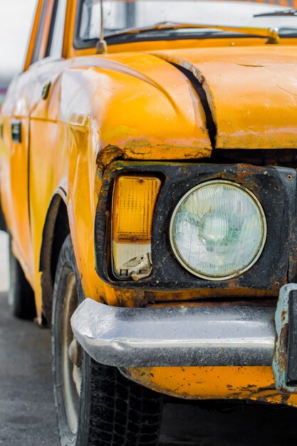 Coche de época amarillo. De cerca. Roto.