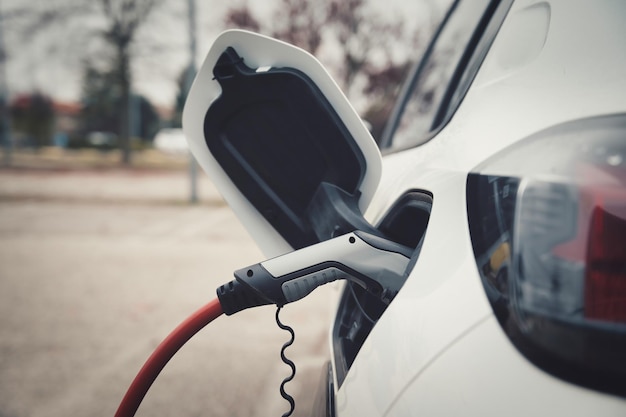 Coche EV o coche eléctrico en la estación de carga con el cable de alimentación enchufado