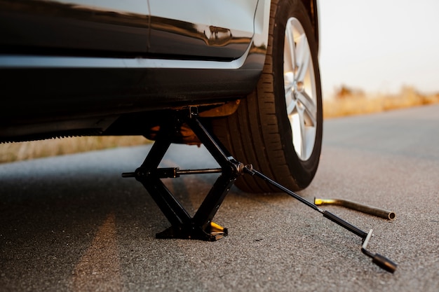 Foto gratuita coche negro levantado por un gato de tornillo