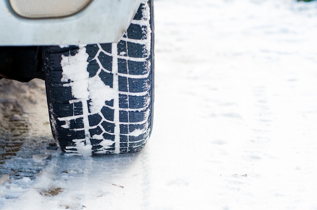 Coche neumáticos en invierno camino cubierto de nieve. Vehículo en el callejón nevado en la mañana en la nieve