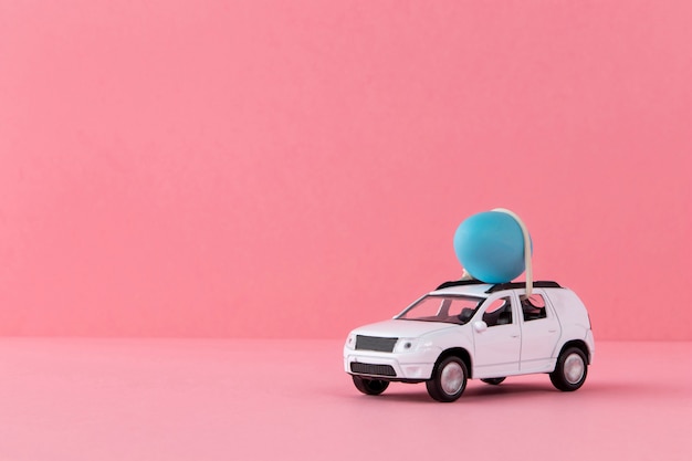 Coche de pascua blanco con huevo azul y fondo rosa.