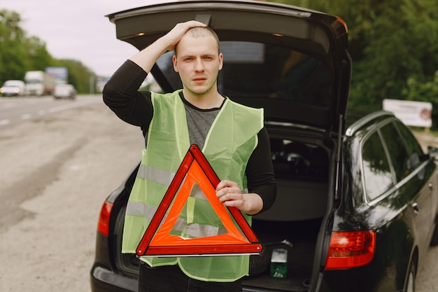 Foto gratuita coche con problemas y un triángulo rojo para advertir a otros usuarios de la carretera.
