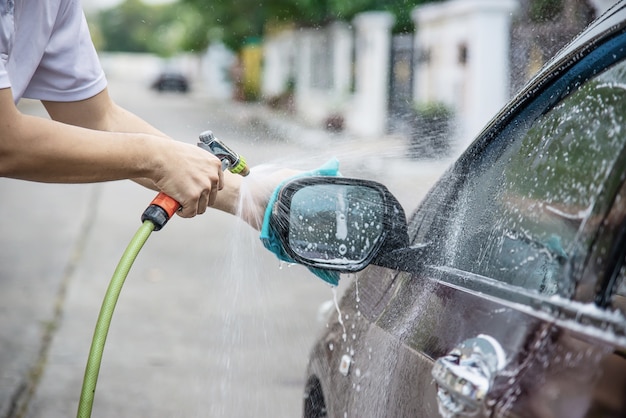 Foto gratuita coche que se lava del hombre usando agua del chorro