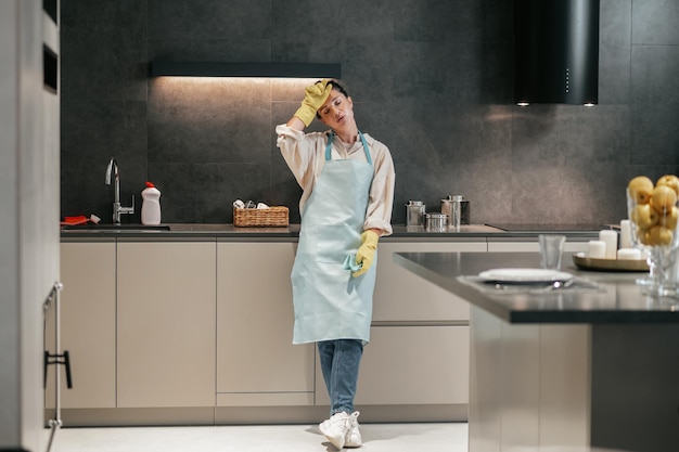 En la cocina. Mujer joven en delantal y guantes en la cocina.