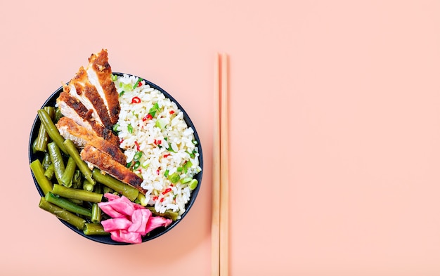 Cocina oriental. Arroz con pollo a la parrilla al estilo japonés, listo para comer, contra un fondo brillante. Jugosa salsa teriyaki de pollo enmarcada en un concepto simple.