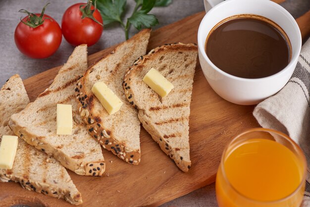 Cocina tradicional para el desayuno. Fotografía de cerca. Mantequilla y pan para el desayuno, taza de café y jugo de naranja.