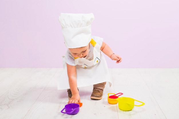 Cocinar al niño jugando con platos de juguete.