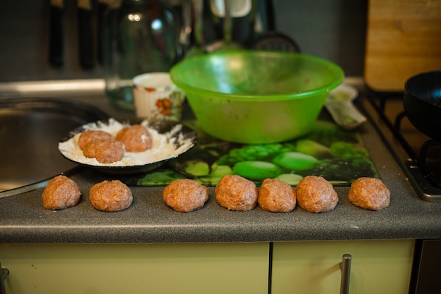 Cocinar albóndigas, carne picada lista se encuentra asando en la mesa de la cocina