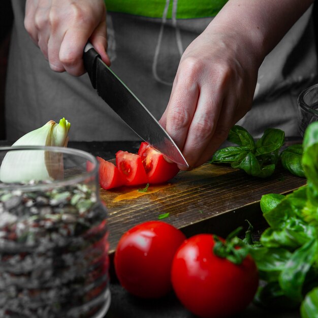 Cocinar cortar tomate sobre tabla de madera