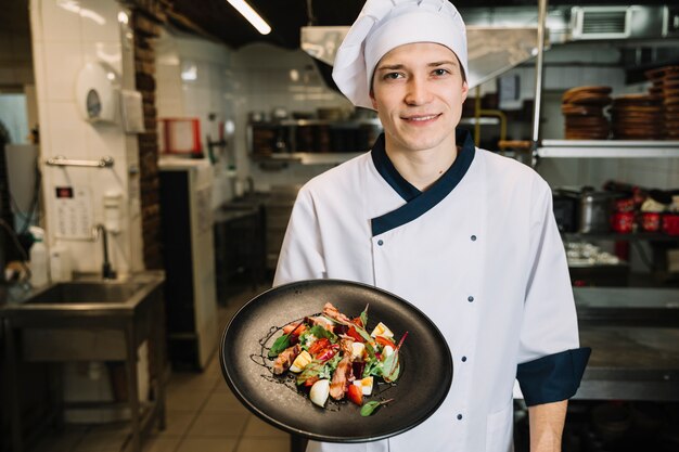 Cocinar mostrando ensalada con carne en plato