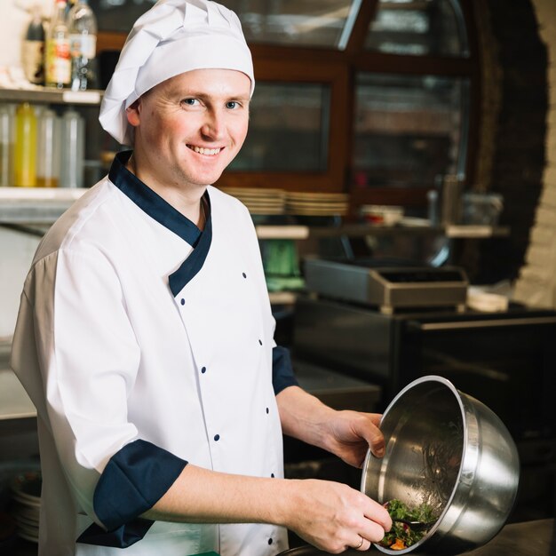 Cocinar de pie con un plato grande de ensalada