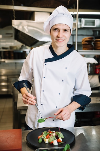 Cocinar poniendo las espinacas en el plato con ensalada.