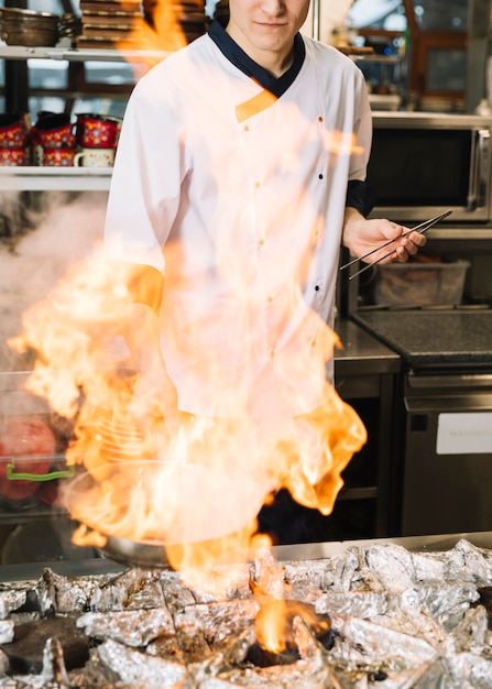 Cocinar sosteniendo la sartén en la mano