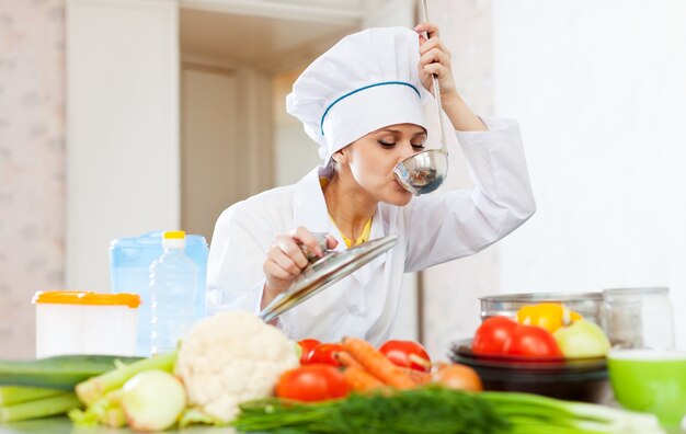 Cocinar en uniforme blanco prueba la sopa de cuchara