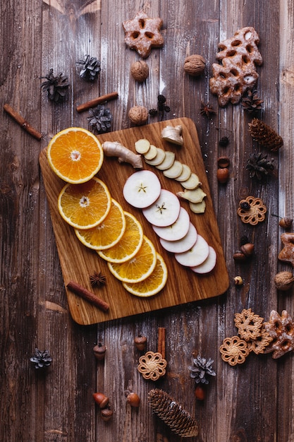 Cocinar vino caliente. Naranjas, manzanas y especies se encuentran en mesa de madera