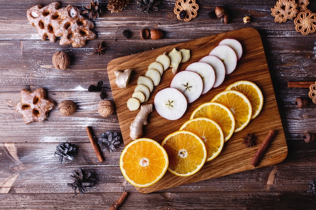 Cocinar vino caliente. Naranjas, manzanas y especies se encuentran en mesa de madera