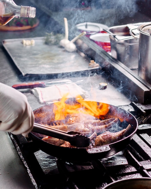 Cocine las costillas para freír carne salada dentro de una sartén de metal negro en la cocina