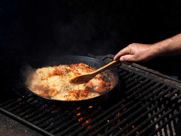 Cocine mezclando arroz con aros de calamares y verduras en una sartén