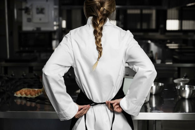 Cocinera en la cocina vestida con delantal y uniforme