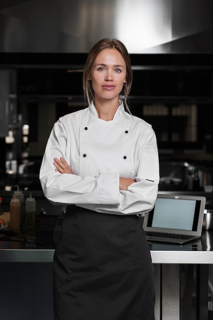 Cocinera en la cocina vestida con delantal y uniforme