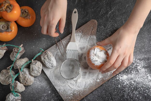 Cocinera decorar caqui con harina sobre superficie negra