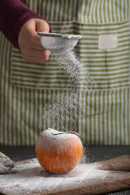 Foto gratuita cocinera derramar harina de caqui dulce en la cocina