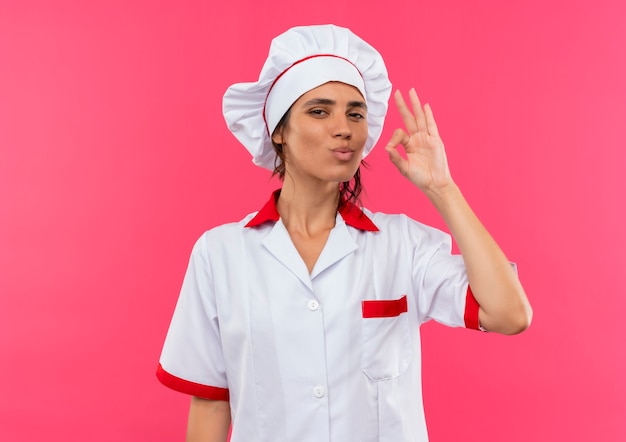 Cocinera joven complacida vistiendo uniforme de chef mostrando delicioso gesto con espacio de copia