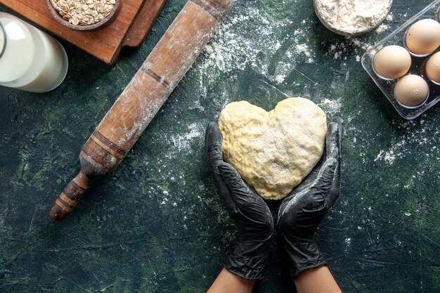 Cocinera de vista superior trabajando con masa en forma de corazón sobre superficie gris oscuro