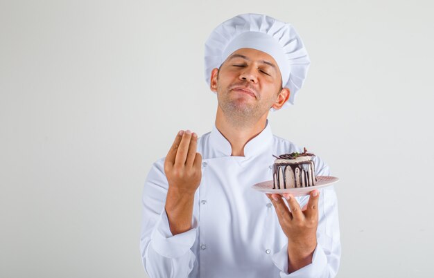 Cocinero chef hombre sosteniendo pastel y haciendo gesto italiano con sombrero y uniforme