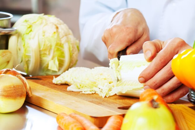 cocinero corta lechuga con cuchillo