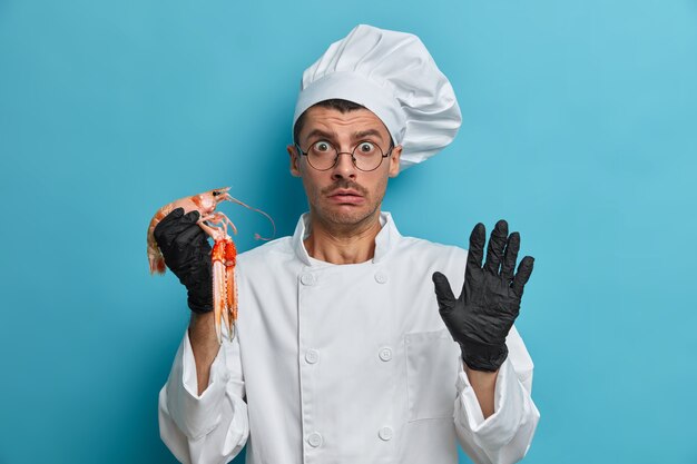 Cocinero desconcertado va a cocinar plato de langosta, temeroso de algo