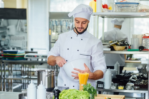 Cocinero feliz del cocinero masculino en la cocina del restaurante.