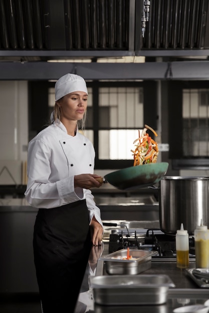 Cocinero femenino en la cocina que fríe la comida