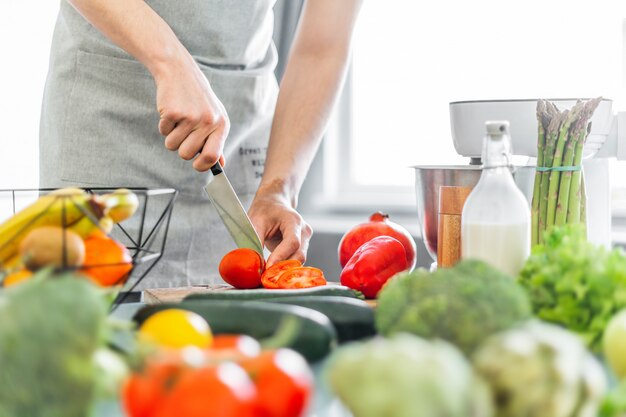 Cocinero del hombre joven que cocina la ensalada sana