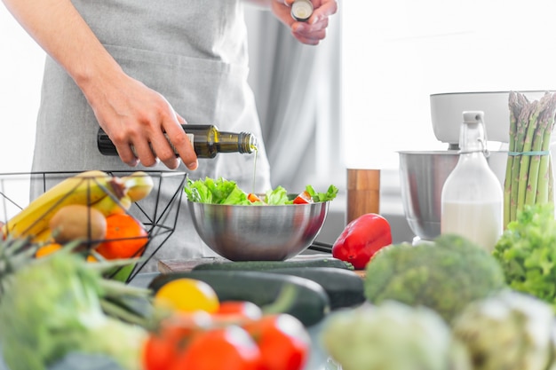 Cocinero del hombre joven que cocina la ensalada sana