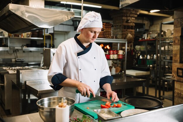 Cocinero joven que corta el tomate a bordo