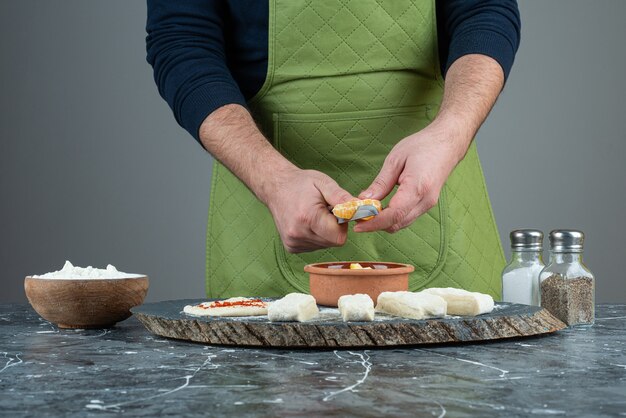 Cocinero masculino corta naranja en trozos sobre la mesa de mármol.
