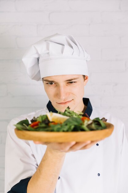 Cocinero mirando plato de madera con ensalada