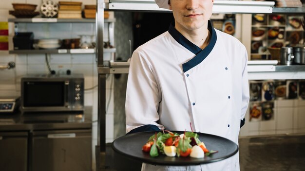 Cocinero con plato de ensalada vegetariana.